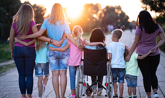 Kinder, Mütter und Betreuuer:innen die sich gemeinsam am Arm nehmend den Sonnenuntergang ansehen.